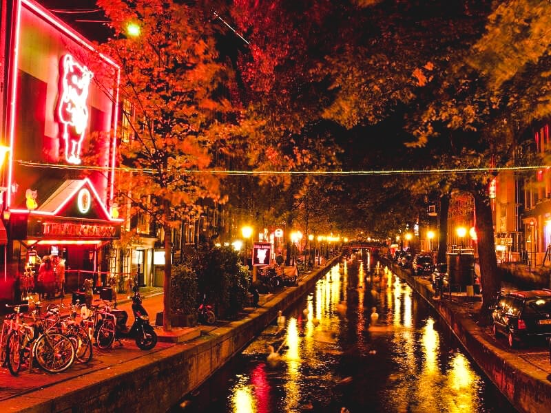 The canal that passes through the red light district in Amsterdam. Shop fronts lit up at night.
