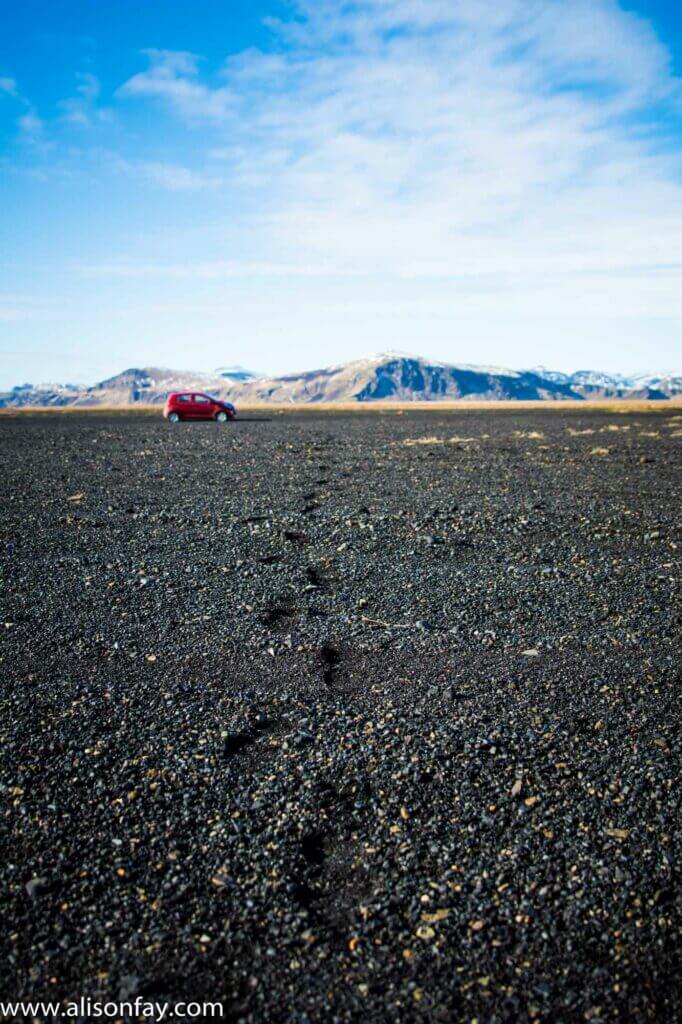 Photograph of a red car in the distance in Iceland