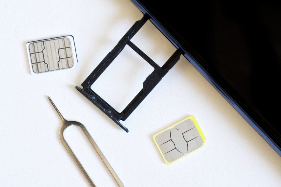 Two miniature nano SIM cards, and a smartphone with an removed tray for two empty slots lie next to the ejector on a white background. Replacing the smartphone number. Macro