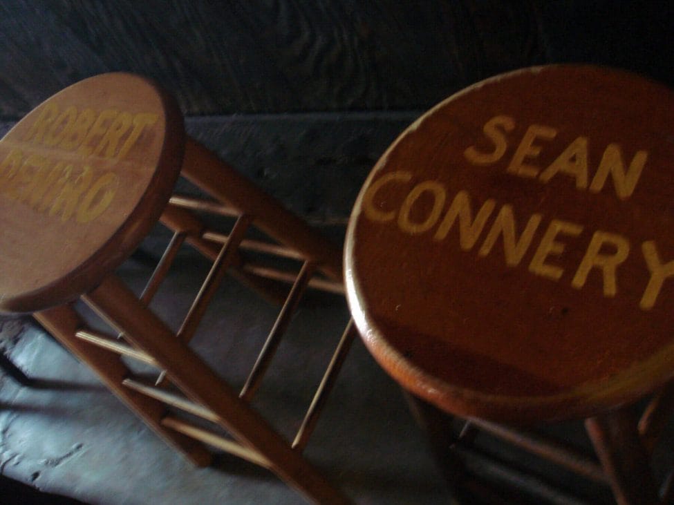 two brown bar stools, painted in a lighter brown colour with the names sean connery and robert deniro.