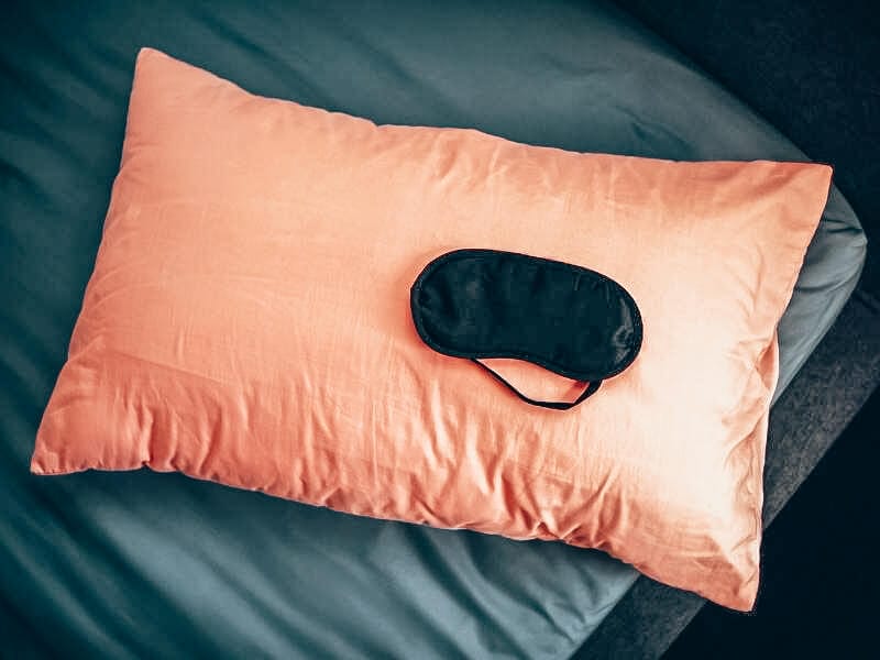 black sleep mask on pink pillow