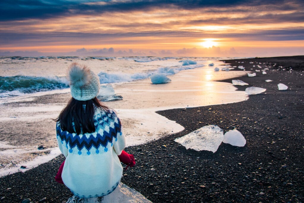 woman sat on diamond beach watching the sunset