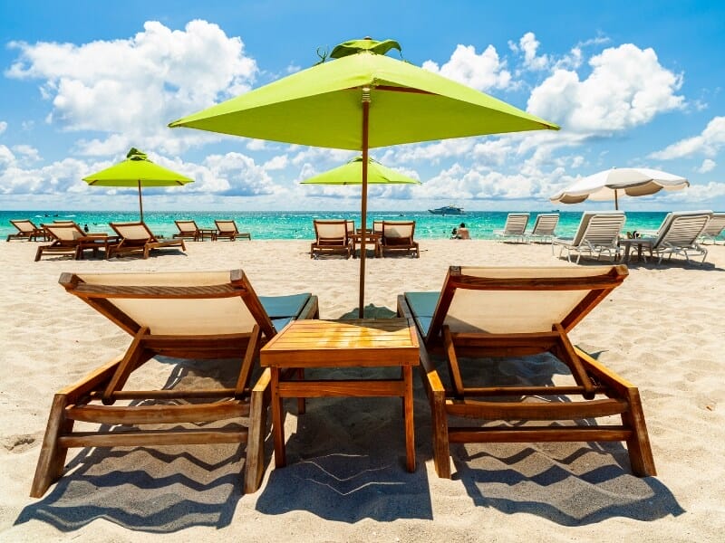 Deck chairs on miami beach with green parasol