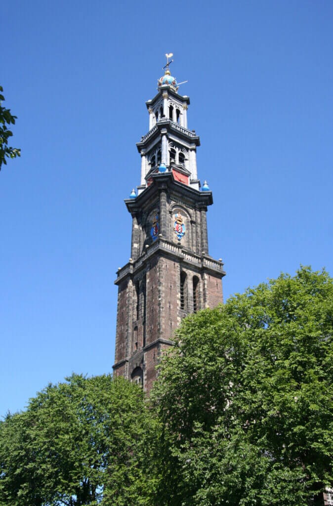 Westerkerk Church tower with trees at the bottom and a blue sky