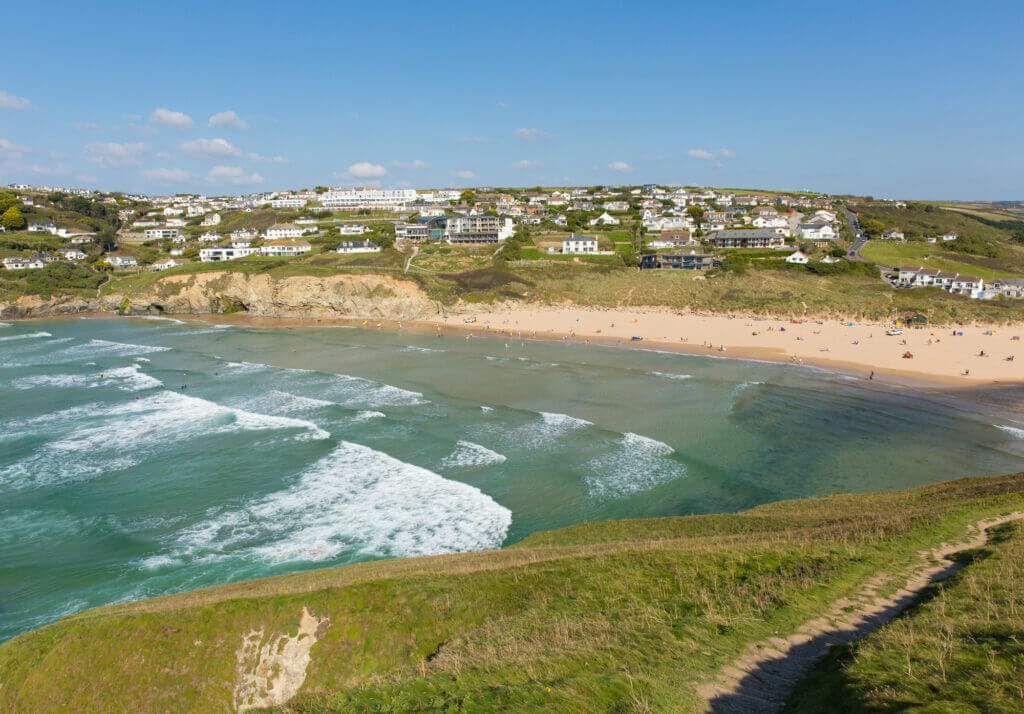 view from a cliff over mawgan port beach, as the tide is coming in.