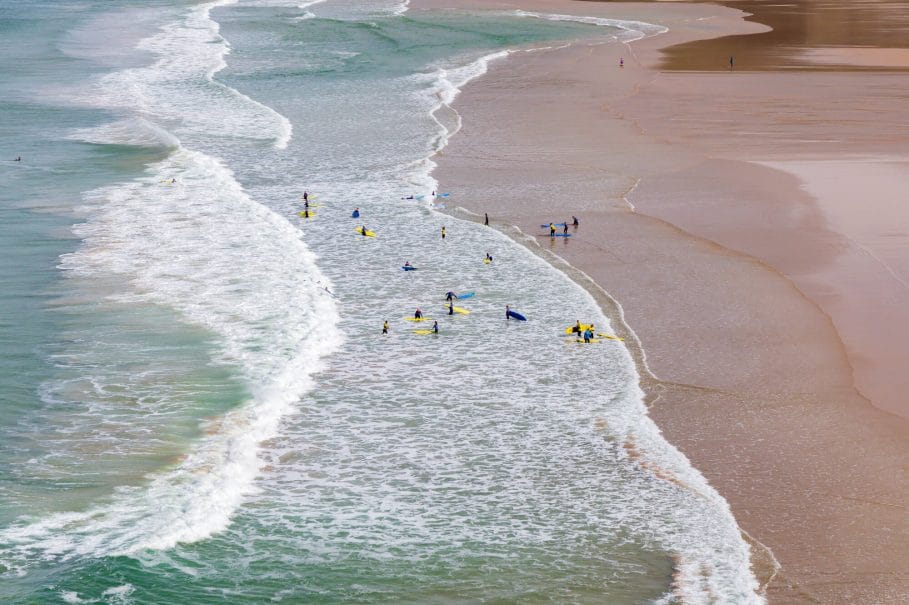 Surfers in the waves off Mawgan Porth Beach, Cornwall, UK