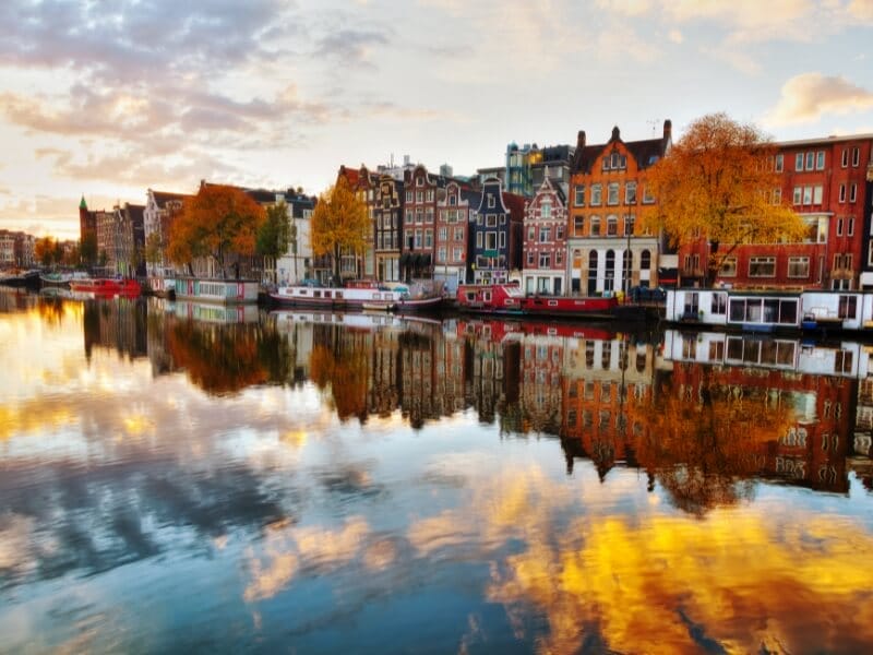 Amsterdam canal in autumn, taken during sunset with the trees and canal houses in reflecting in the water.