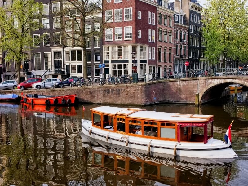 Photo of a traditional wooden canal boat cruising along the waterways in Amsterdam.