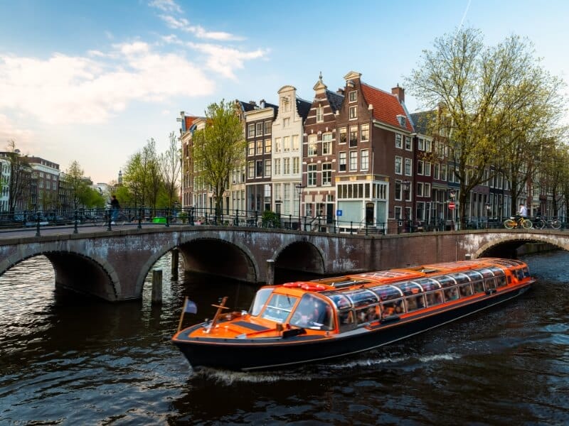 Lovers canal boat cruising under a bridge in Amsterdam