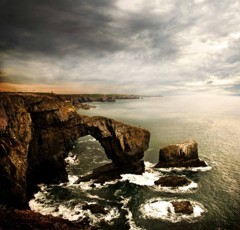 A high angle shot of the Green Bridge of Wales in the United Kingdom with a cloudy gray sky in the background