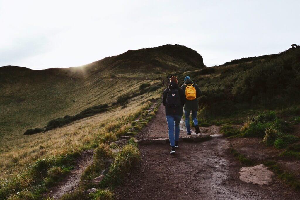 man in blue jacket and blue denim jeans walking on pathway